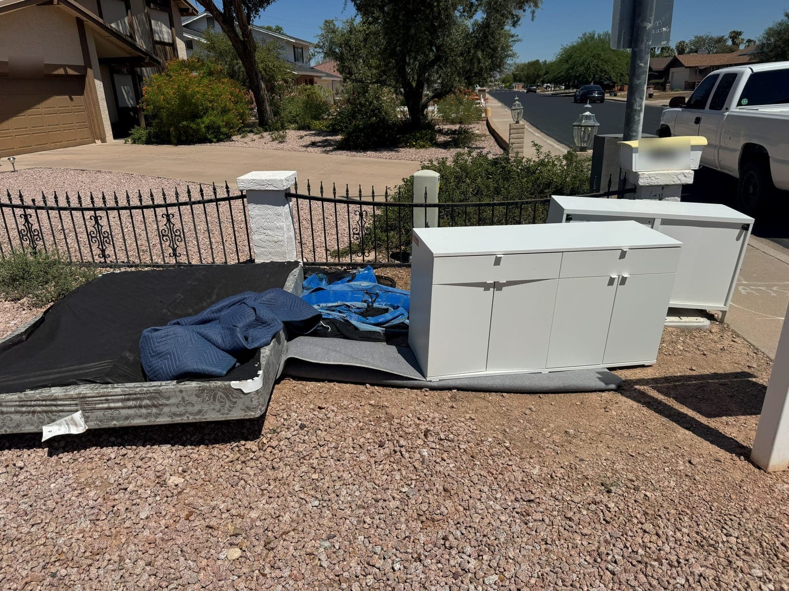Mattress, box spring, and two white storage cabinets staged at the curb for junk removal pickup in the East Valley