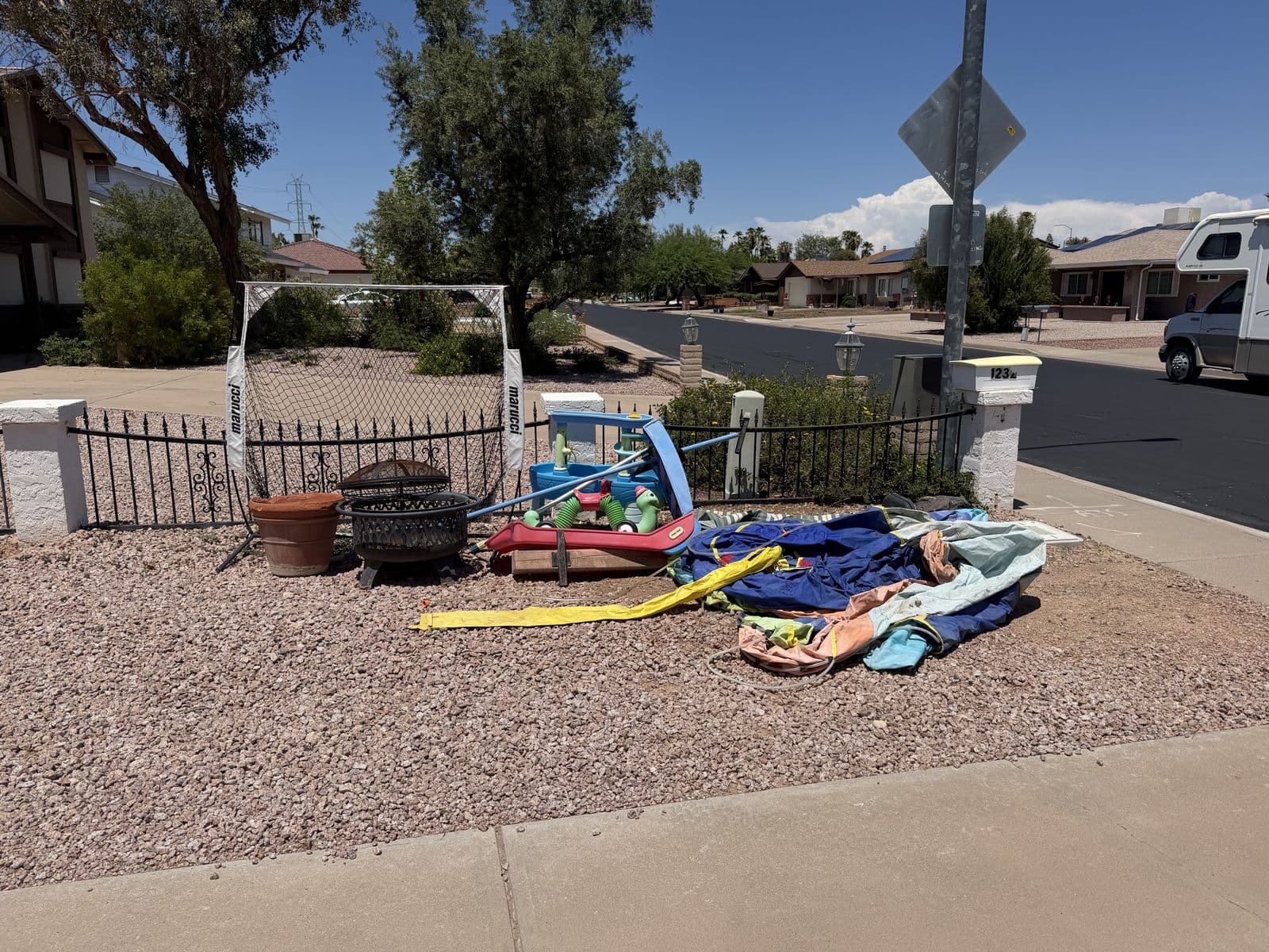 Curbside pile of backyard toys, a fire pit, and yard gear staged for junk removal pickup