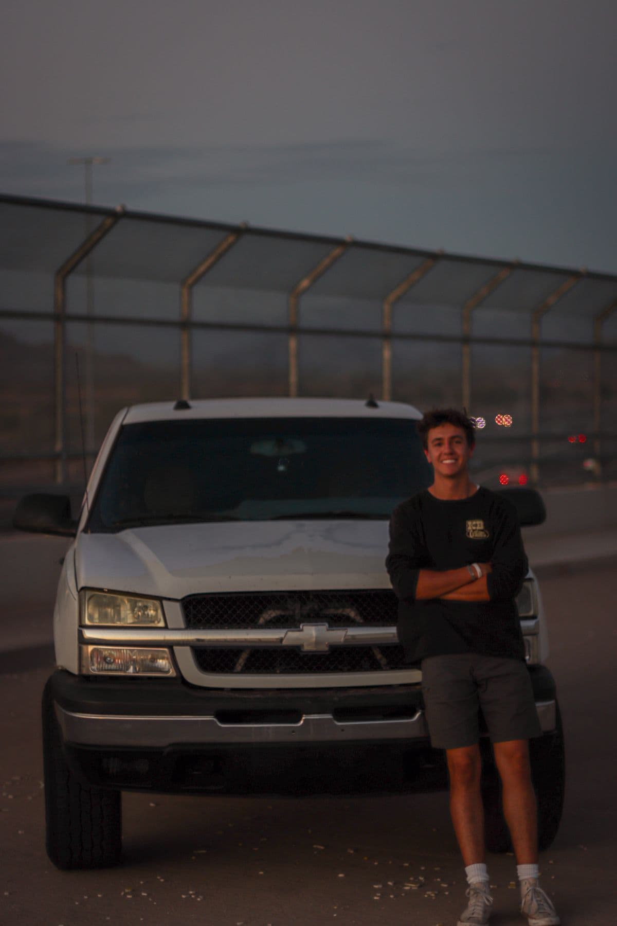 Trevor Harris, owner of Sonoran Standard, standing in front of his white Chevy work truck at dusk